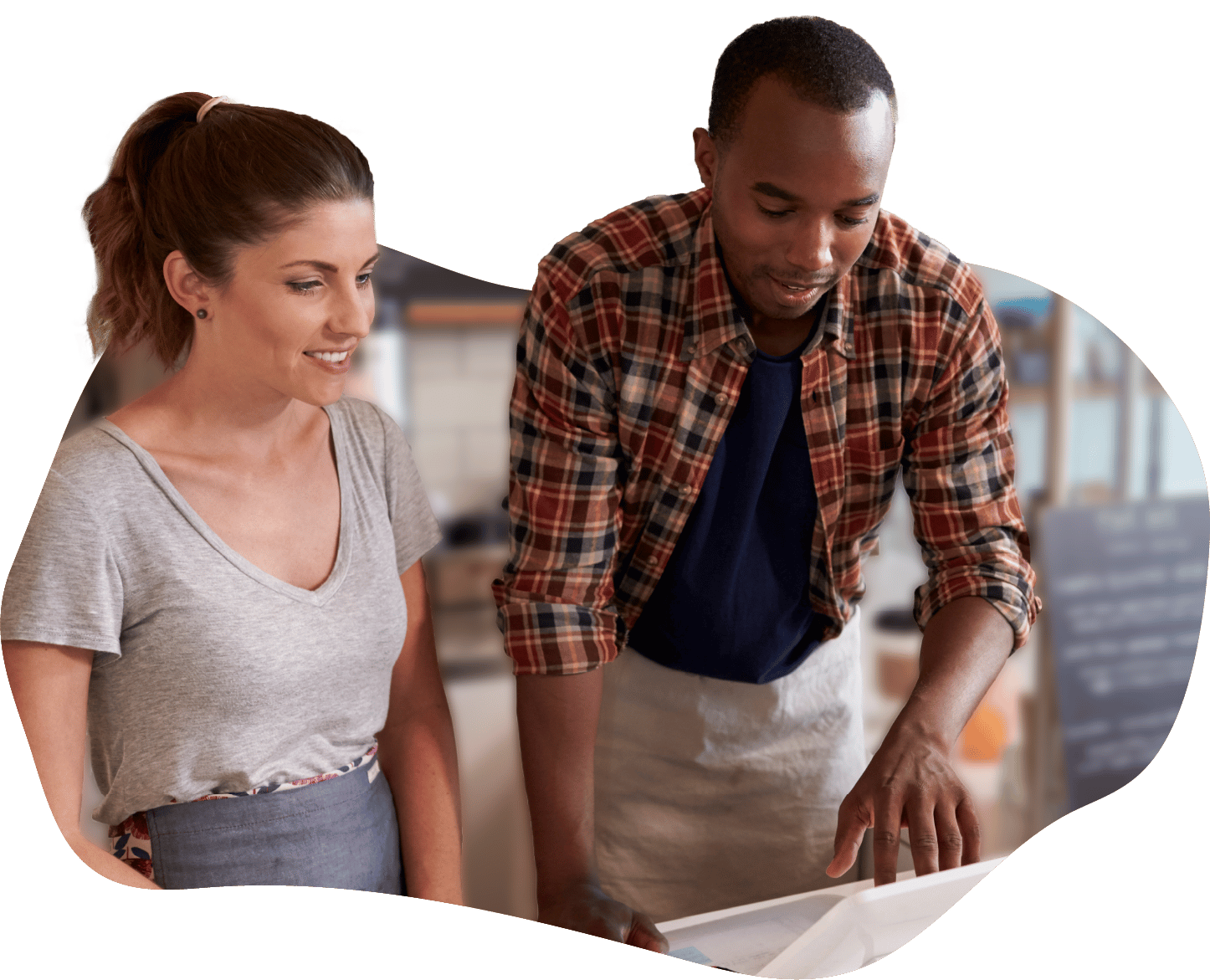 A focused man and woman looking at a Point of Sale (POS) system in a coffee shop, reflecting the critical process of hiring the right team for a food service business. The image underscores the importance of a reliable, customer-focused staff, accompanying a guide on writing job descriptions, finding candidates, conducting interviews, and onboarding new hires for a successful food service operation.